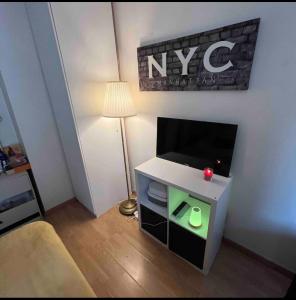 een kleine woonkamer met een tv en een lamp bij Private room in Parijs