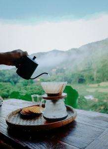 a person pouring a drink into a cup on a table at Imsuk Bo Klua in Ban Pha Khap