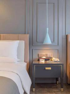 a bedroom with a bed and a side table with a lamp at Lano Hotel Guizhou Zunyi Xinpu New District Linda Sunshine City in Zunyi