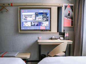 HengshuiにあるThank Inn Chain Hotel Hebei hengshui wuqiang zhenxing roadの壁にテレビとデスクが備わる客室です。
