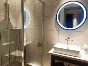 een badkamer met een douche, een wastafel en een spiegel bij Lano Hotel Xilinhot Taipusi Banner South Jianshe Road 