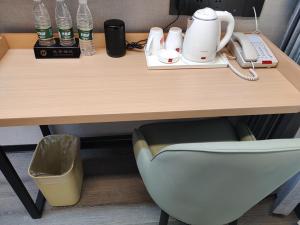 a wooden desk with a phone and a chair at it at Thank Inn Plus Hotel Shandong Jining Liangshan County Xuji Zhengyang in Jining