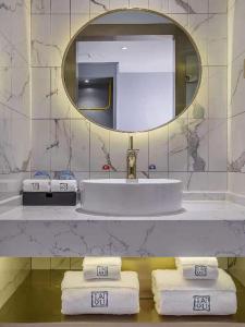 ein Badezimmer mit einem Waschbecken, einem Spiegel und Handtüchern in der Unterkunft Lano Hotel Guizhou Zunyi Xinpu New District Linda Sunshine City in Zunyi