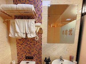 ein Bad mit einem Waschbecken und einem Spiegel in der Unterkunft Thank Inn Plus Hotel Jiangsu Taizhou Dainan Tuanjie in Shiyan
