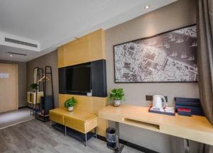 a room with a desk and a tv on a wall at LanOu Hotel Zhengzhou High-Tech Zone Headquarter Enterprise Base in Zhengzhou