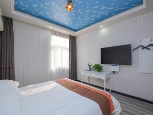 een slaapkamer met een bed en een flatscreen-tv bij JUN Hotels Jiangsu Nanjing Railway Station Sun Yat-sen Mausoleum Scenic Area in Nanjing
