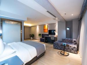 Habitación de hotel con cama, sofá y escritorio en Lano Hotel Guiyang High Speed Rail North Station Dream City, en Guiyang