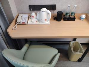 a desk with a phone and a chair under it at Thank Inn Plus Hotel Shandong Jining Liangshan County Xuji Zhengyang in Jining