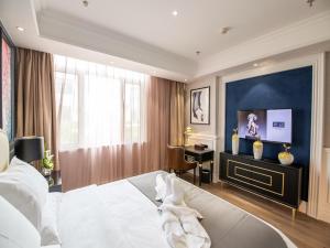 a bedroom with a white bed and a desk in it at Lano Hotel Hebei Chengde Shuangqiao District Herun New City in Chengde