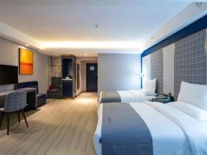 een grote hotelkamer met 2 bedden en een bureau bij Lano Hotel Guiyang High Speed Rail North Station Dream City in Guiyang