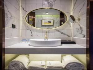 a bathroom with a sink and a mirror and towels at Lano Hotel Zhenjiang South High-speed Railway Station Baolong Plaza in Zhenjiang