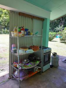 a kitchen with a stove and a shelf with dishes at Ravehei smile relais 2 moorea in Afareaitu