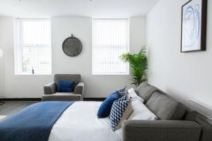 a bedroom with a bed and a couch and windows at Bootle(Liverpool) Modern 2Bed Ft in Bootle