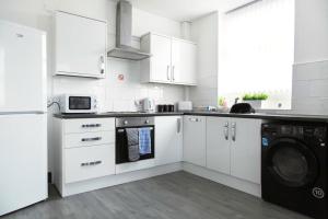 a white kitchen with white cabinets and a dishwasher at Bootle(Liverpool) Modern 2Bed Ft in Bootle