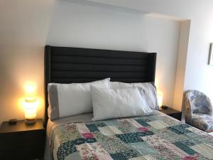 a bedroom with a bed with a quilt and two lamps at Albano, Ocean view and pool near Miraflores and airport in Lima