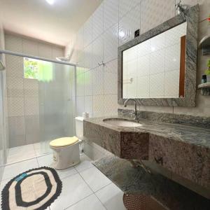 La salle de bains est pourvue de toilettes, d'un lavabo et d'un miroir. dans l'établissement Sítio Ribeirão Bonito, à Pinheiral