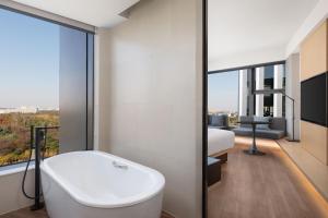 a bathroom with a white bath tub and a bedroom at Fairfield by Marriott Shanghai Lingang Special Area in Shanghai