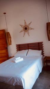 een slaapkamer met een wit bed en een houten hoofdeinde bij Villa Maria in Uruçuca