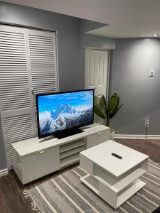 sala de estar con TV de pantalla plana en un centro de entretenimiento blanco en Cozy basement in Brampton, en Brampton