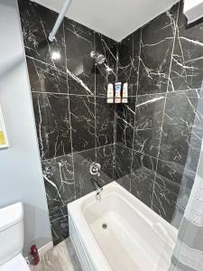 a black tiled bathroom with a white bath tub at Cozy basement in Brampton in Brampton