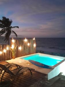 a swimming pool with chairs and the ocean at night at Aloha in Icapuí