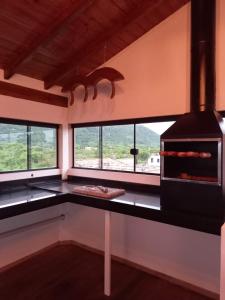 a kitchen with a counter with a stove and windows at Apartamento Encantador Praia da Pinheira in Palhoça