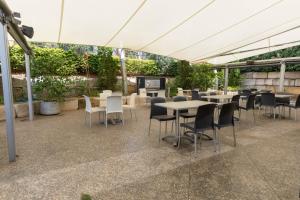 een patio met tafels en stoelen en een televisie bij Highfields Motel Toowoomba in Highfields