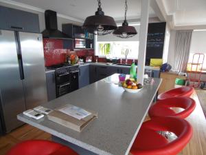 una cucina con bancone e sgabelli rossi di Rosemount B&B by the Sea St Clair a Dunedin