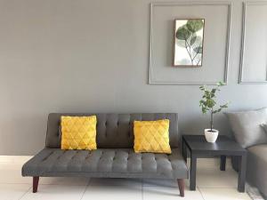 - un canapé gris avec deux oreillers jaunes dans le salon dans l'établissement HCK28 Platino High View｜3min walk Paradigm｜Sutera, à Johor Bahru