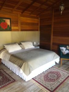 a bedroom with a large bed and a chair at Cabanas do Empório Aparados da Serra in Bom Jardim da Serra