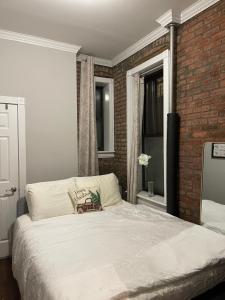 a bedroom with a white bed with a brick wall at Private one bedroom one bathroom in New York