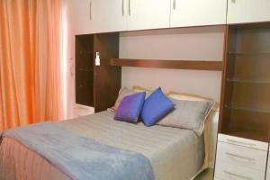um quarto com uma cama com duas almofadas azuis em Lindo apto 2 quartos quadra mar em Balneário Camboriú