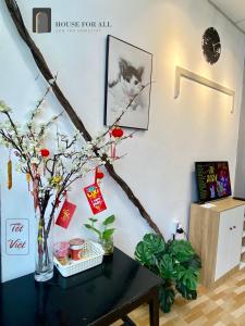 HOUSE FOR ALL - CANTHO HOMESTAY في كان ثو: طاولة مع مزهرية مع قطة على الحائط