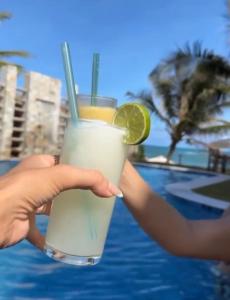 a person holding a drink with a slice of lime at Casa Garça - 4 Suítes - Super Piscina - Pé na Areia - em Maceió in Maceió