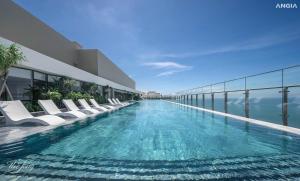 a hotel swimming pool with white chairs and the ocean at The Sóng luxury apartments in Vung Tau in Vung Tau