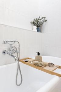 a bathroom with a bath tub and a wooden shelf at Hazel House Goulburn in Goulburn