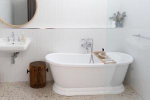 een witte badkamer met een bad en een wastafel bij Hazel House Goulburn in Goulburn