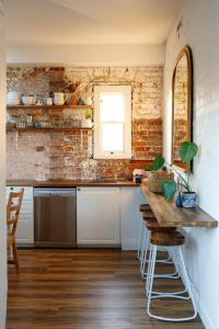a kitchen with white cabinets and a brick wall at Hazel House Goulburn in Goulburn