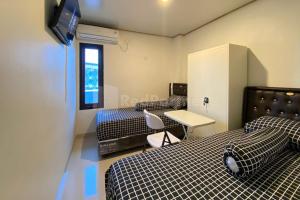 Habitación con 2 camas, mesa y TV. en SwCo Living Palembang, en Palembang