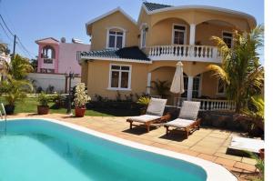 a house with a swimming pool in front of a house at Villa Sundara Mauritius in Trou aux Biches