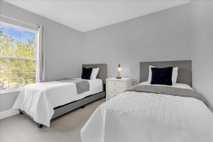 a white bedroom with two beds and a window at 4 Bedrooms 35 Bathrooms Lake Berkley 938 Pt in Kissimmee +32 photos