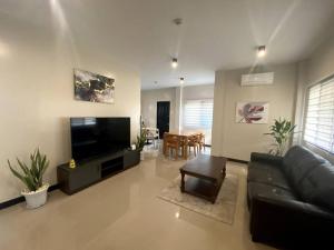 sala de estar con sofá de cuero negro y TV de pantalla plana en Beach House Retreat in Argao en Argao