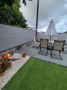 un patio con mesa, sillas y sombrilla en Black and white vacation home en Ceiba
