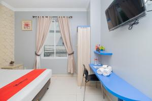 een slaapkamer met een bed, een bureau en een televisie bij RedDoorz Plus @ Cideng Barat in Jakarta