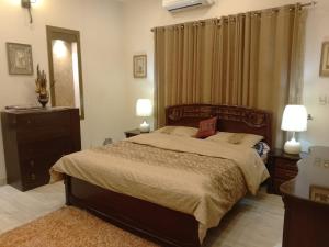 - une chambre avec un lit, deux lampes et un miroir dans l'établissement MJS Entire New Designer House, 5 BR, 13 bed, 2 living, reclining sofas, Italian kitchen, 6 bath, garage, side garden at prime location of Bahria Town, Islamabad, à Rawalpindi
