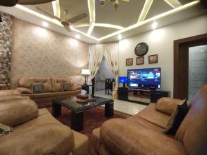 Il comprend un salon avec des canapés et une télévision à écran plat. dans l'établissement MJS Entire New Designer House, 5 BR, 13 bed, 2 living, reclining sofas, Italian kitchen, 6 bath, garage, side garden at prime location of Bahria Town, Islamabad, à Rawalpindi