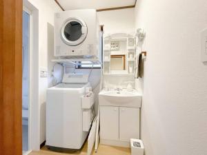 a white bathroom with a sink and a washing machine at 川の音 Kawanone in Izu