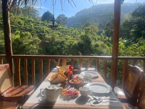 einen Tisch mit Speisen auf einem Balkon mit Aussicht in der Unterkunft Ella Rock Grun Cottage in Ella