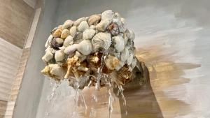 a sculpture of shells on a wall in water at SHANTI SURF CAMP in El Paredón Buena Vista