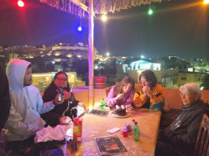 een groep mensen die 's avonds rond een tafel in een restaurant zitten bij The Desert Blabla Hostel in Jaisalmer